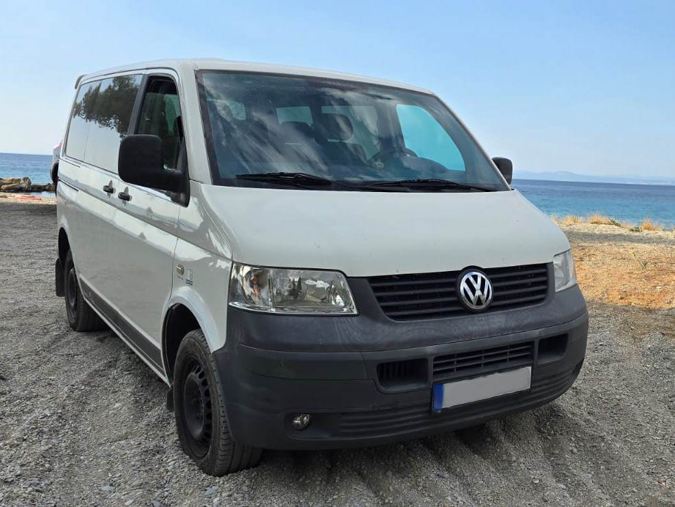 Microbuz Volkswagen alb parcat pe o plajă, cu marea în fundal